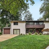 a view of a house with a yard and a large tree