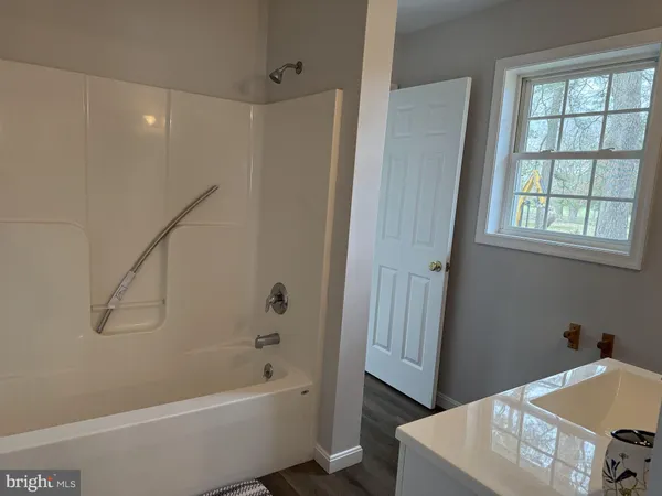 a bathroom with a tub a sink and a window
