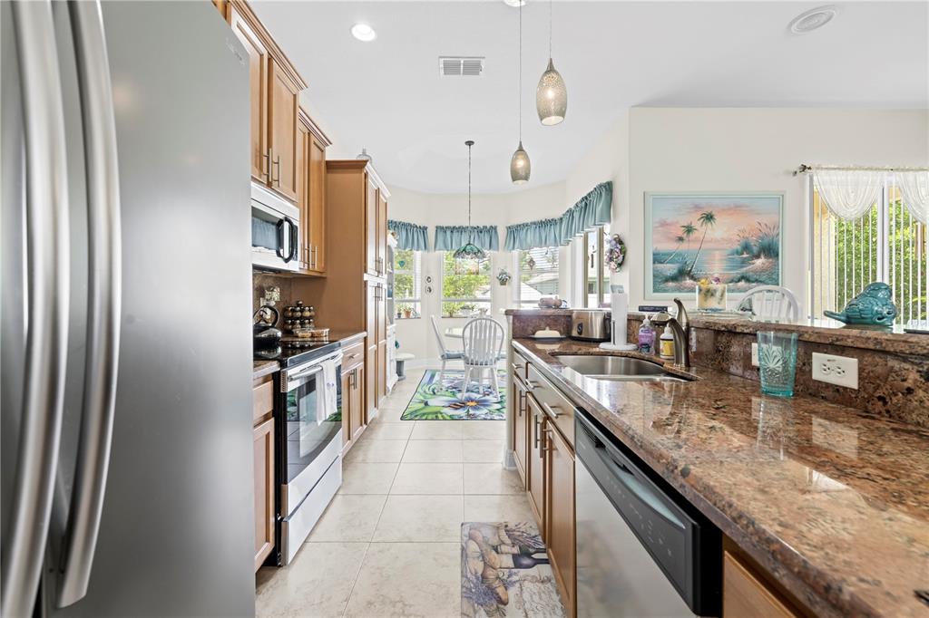 1245 Coble Road Spring Hill, FL 34608 - Photo 32 of 50 a kitchen with stainless steel appliances granite countertop a refrigerator a stove and a sink
