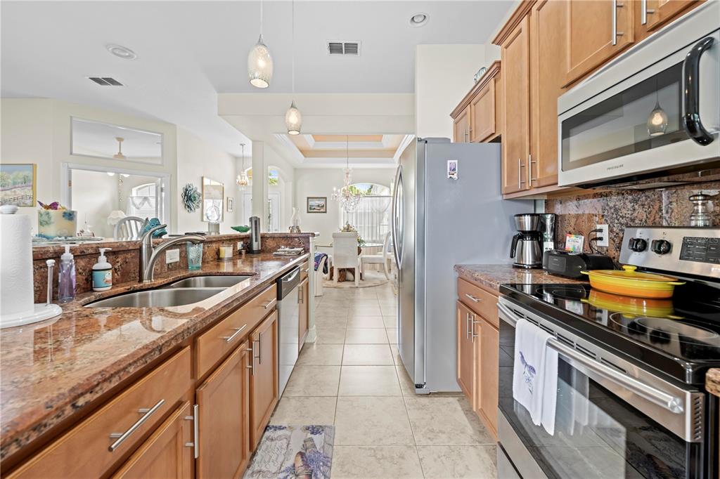1245 Coble Road Spring Hill, FL 34608 - Photo 35 of 50 a kitchen with stainless steel appliances granite countertop a stove a sink and a refrigerator