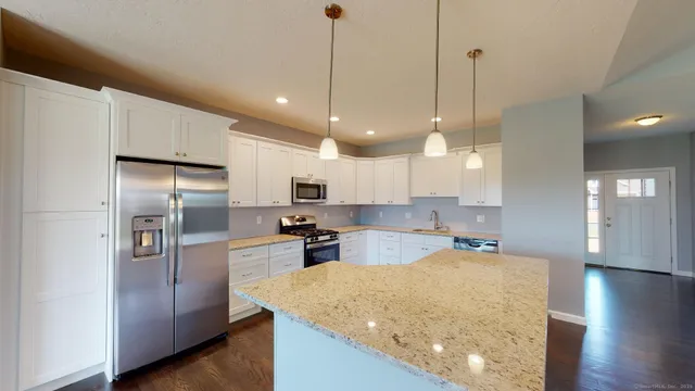 a kitchen with stainless steel appliances granite countertop a refrigerator a sink a stove and a wooden floors