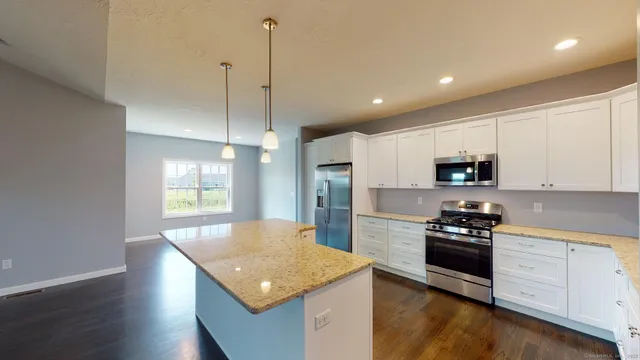 a kitchen with stainless steel appliances granite countertop a sink a stove and a wooden floors