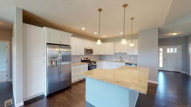 a kitchen with stainless steel appliances granite countertop a refrigerator a sink a stove and a wooden floors