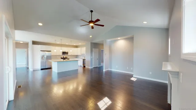 a view of a kitchen and an empty room with wooden floor