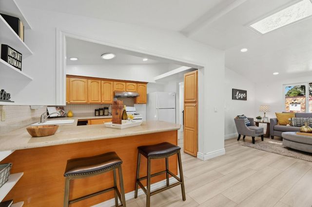 a kitchen with stainless steel appliances granite countertop a stove a sink dishwasher and a refrigerator with wooden cabinets