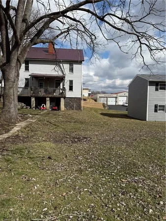 a view of a house with a large tree and a wooden fence