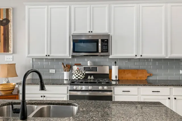 a kitchen with stainless steel appliances granite countertop a stove a sink and a microwave