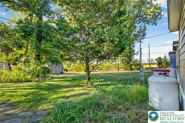 a backyard of a house with large trees and wooden fence