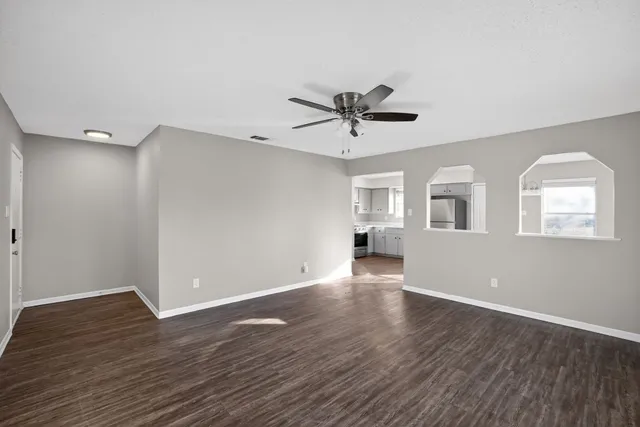 a view of an empty room with wooden floor and a window