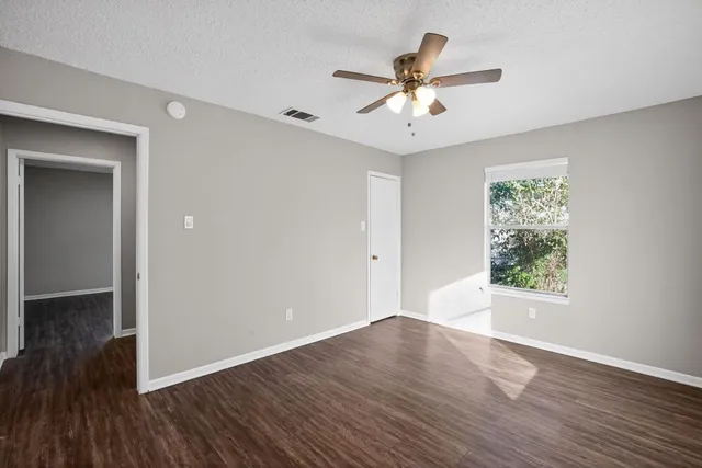 a view of an empty room with wooden floor and a window