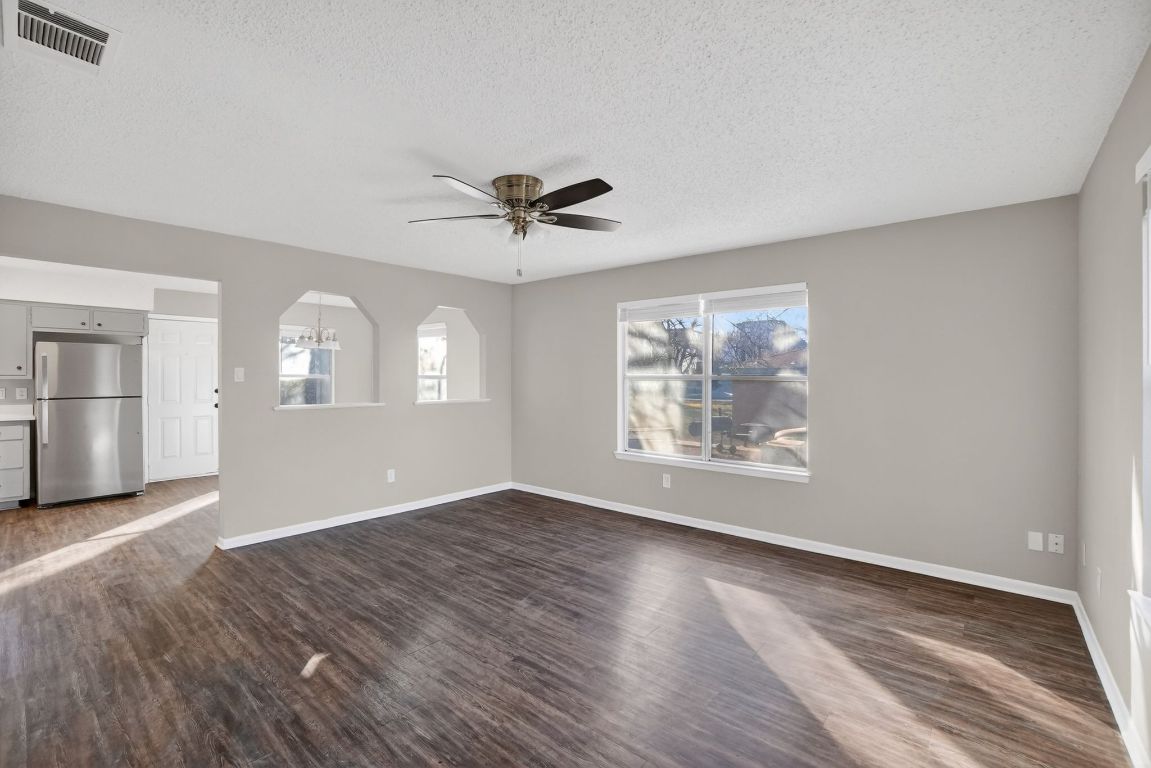 1505 Timber Street Georgetown, TX 78626 - Photo 7 of 22 Unfurnished living room featuring a textured ceiling, ceiling fan, and dark wood-style floors