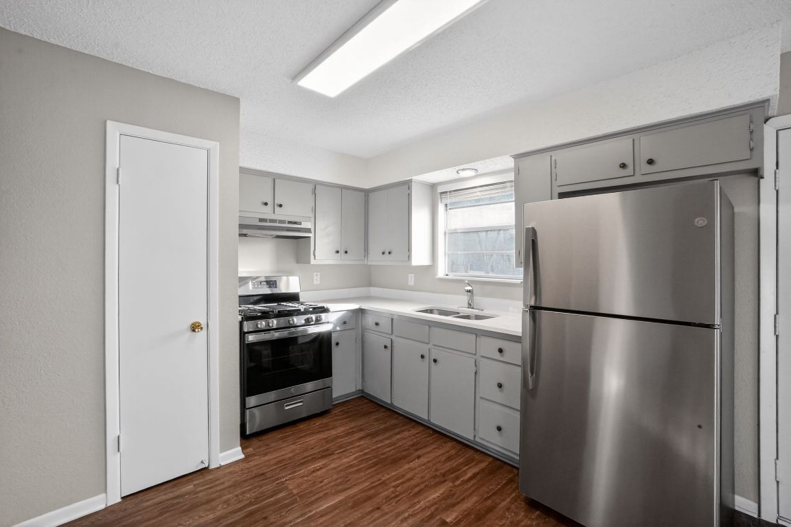 1505 Timber Street Georgetown, TX 78626 - Photo 10 of 22 Kitchen with stainless steel appliances, gray cabinetry, light countertops, dark wood-style floors, and under cabinet range hood