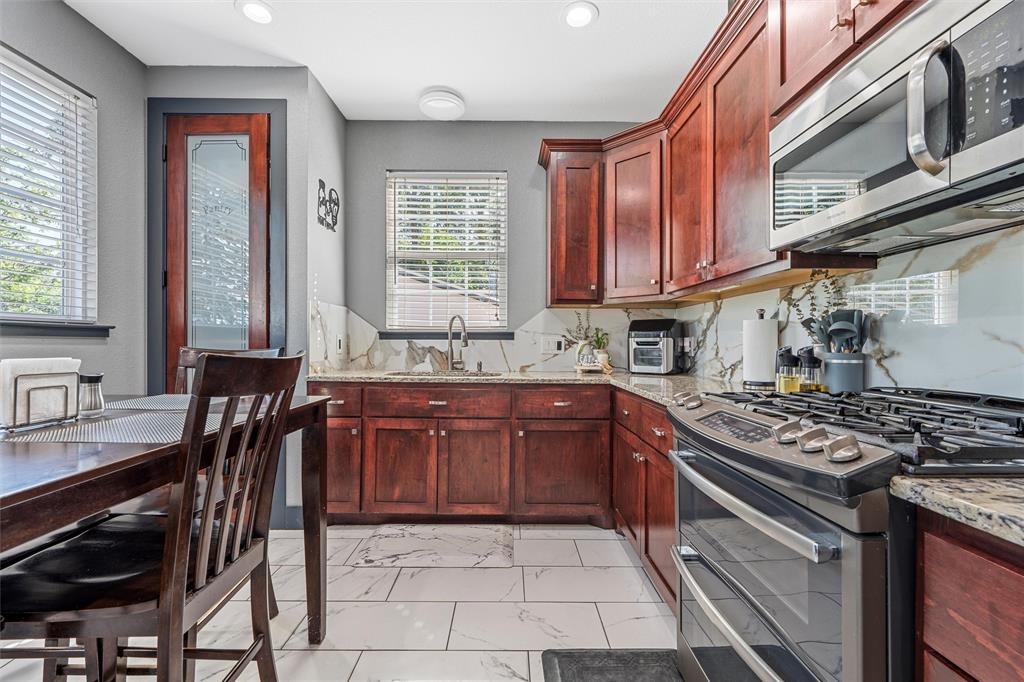 1205 North 17th Street Waco, TX 76707 - Photo 11 of 38 Kitchen featuring appliances with stainless steel finishes, dark brown cabinets, light marble finish flooring, and recessed lighting