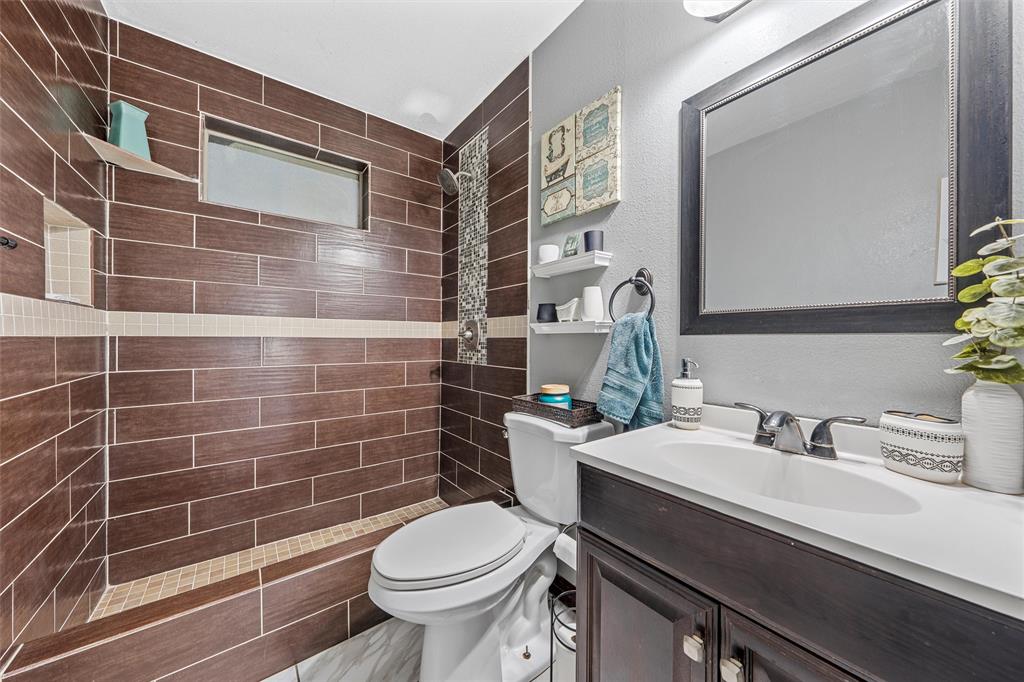 1205 North 17th Street Waco, TX 76707 - Photo 13 of 38 Bathroom featuring a tile shower, vanity, and a textured wall
