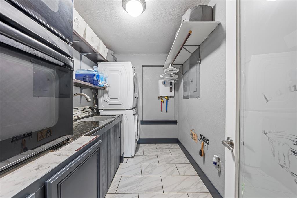 1205 North 17th Street Waco, TX 76707 - Photo 16 of 38 Laundry room with stacked washer and clothes dryer, a textured ceiling, and light marble finish flooring