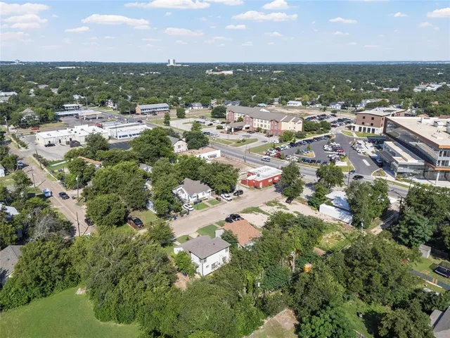 an aerial view of residential houses with outdoor space and trees