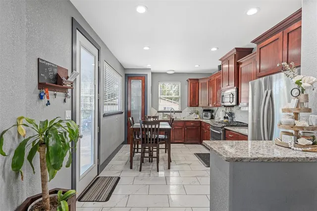 a kitchen with stainless steel appliances granite countertop a refrigerator a stove a sink a dining table and chairs