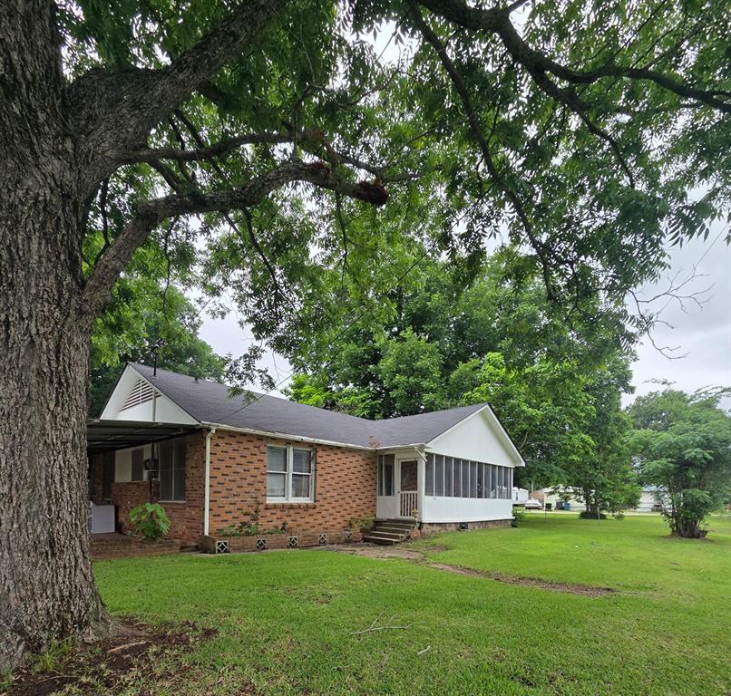 301 Old Plain Dealing Road Benton, LA 71006 - Photo 1 of 19 Brick-clad exterior with a dark shingle roof, featuring a screened-in porch and a covered carport