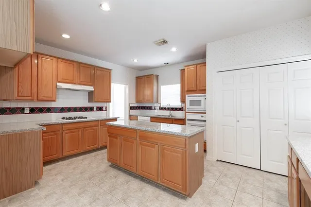 a kitchen with stainless steel appliances granite countertop a refrigerator and a stove top oven