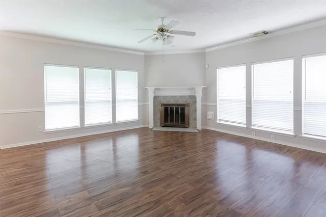 an empty room with wooden floor fireplace and windows