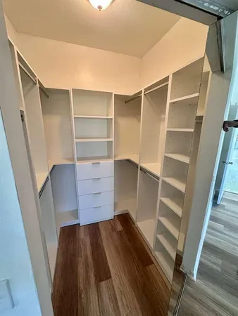 an empty room with wooden floor closet and windows