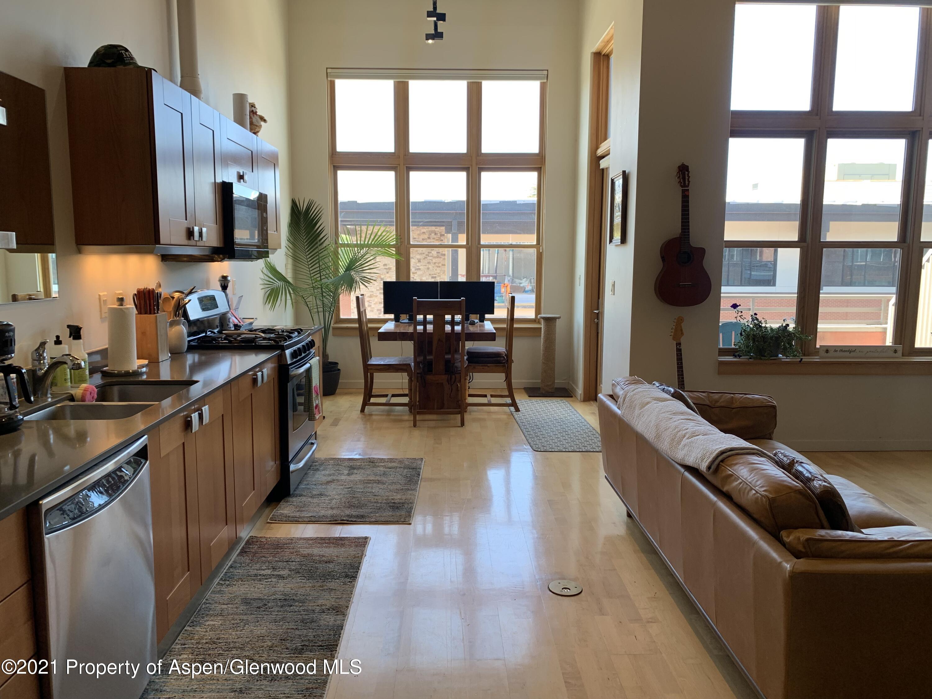 a living room with stainless steel appliances granite countertop a couch and a view of living room