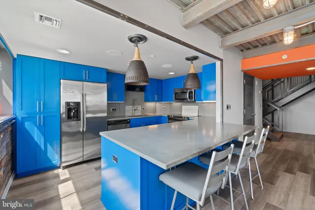 a kitchen with stainless steel appliances kitchen island granite countertop a table chairs in it and wooden floors