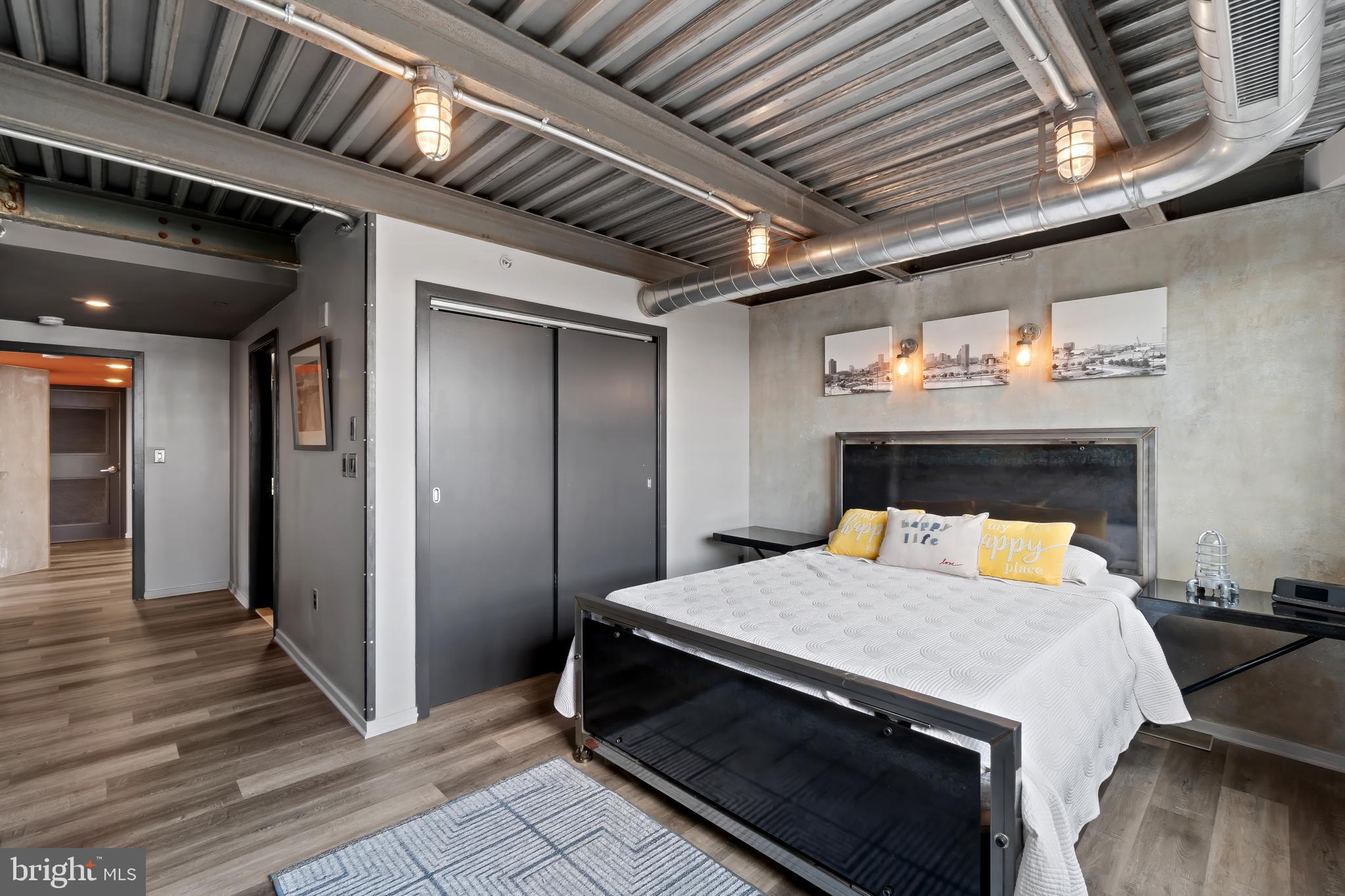 1200 Steuart Street, Unit 1119 Baltimore, MD 21230 - Photo 23 of 37 a bedroom with a bed and wooden floor