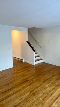 a view of an empty room with wooden floor and stairs