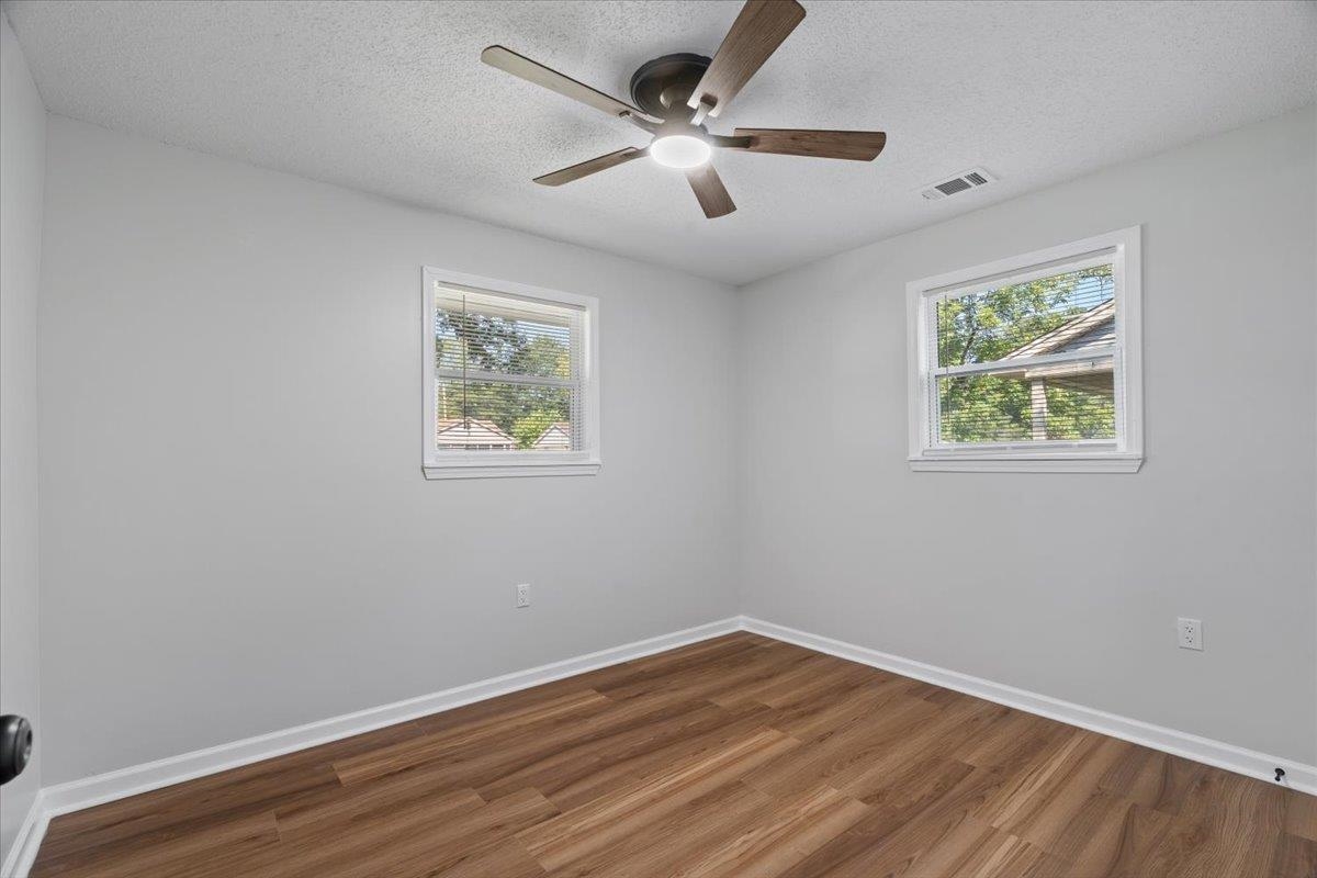 524 McDermitt Road Memphis, TN 38120 - Photo 16 of 32 Wood-finish flooring, two windows with white trim, and a ceiling fan with integrated lighting