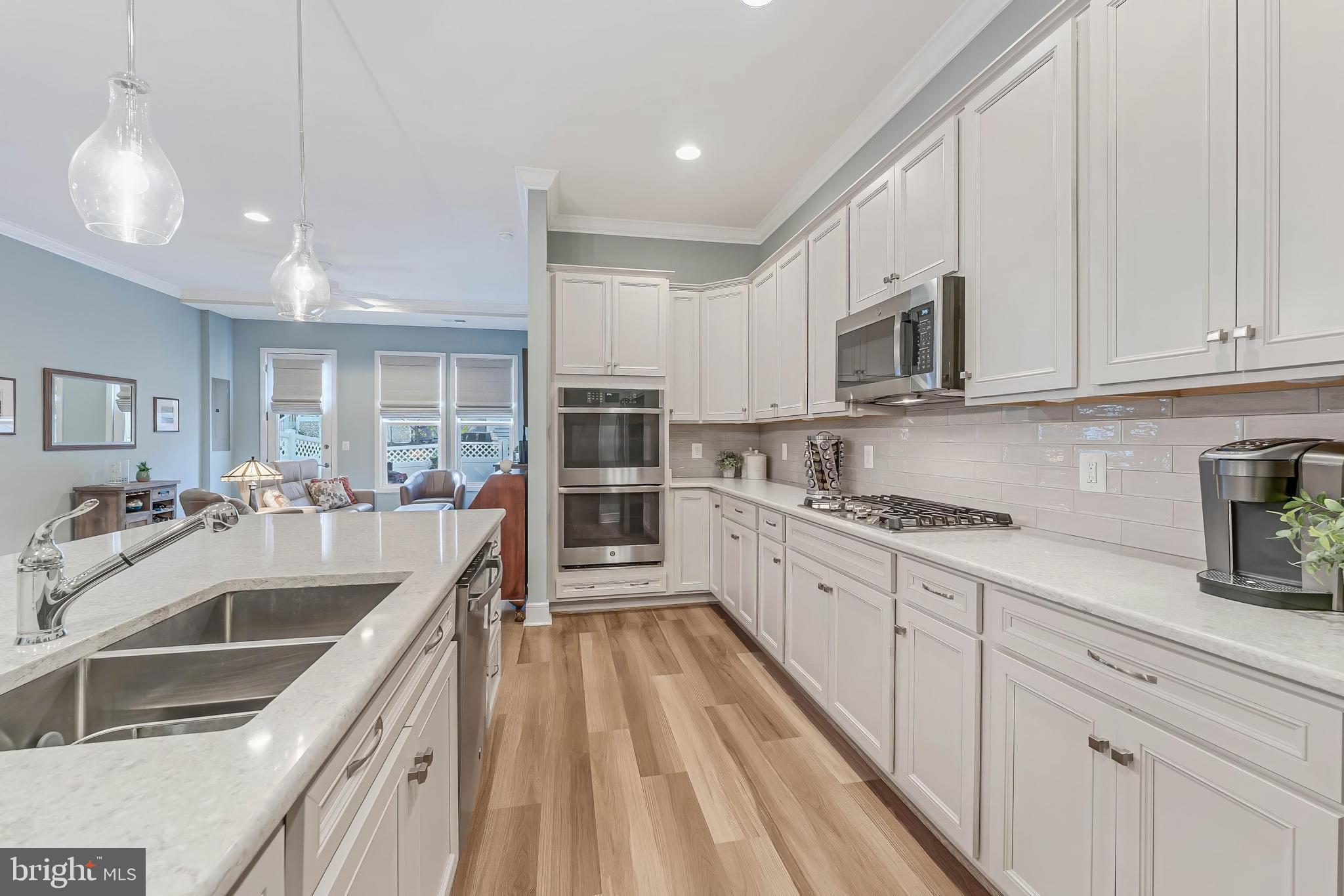 23707 Kinston Ferry Terrace Ashburn, VA 20148 - Photo 5 of 42 a view of a kitchen with stainless steel appliances granite countertop a sink dishwasher stove and white cabinets with wooden floor