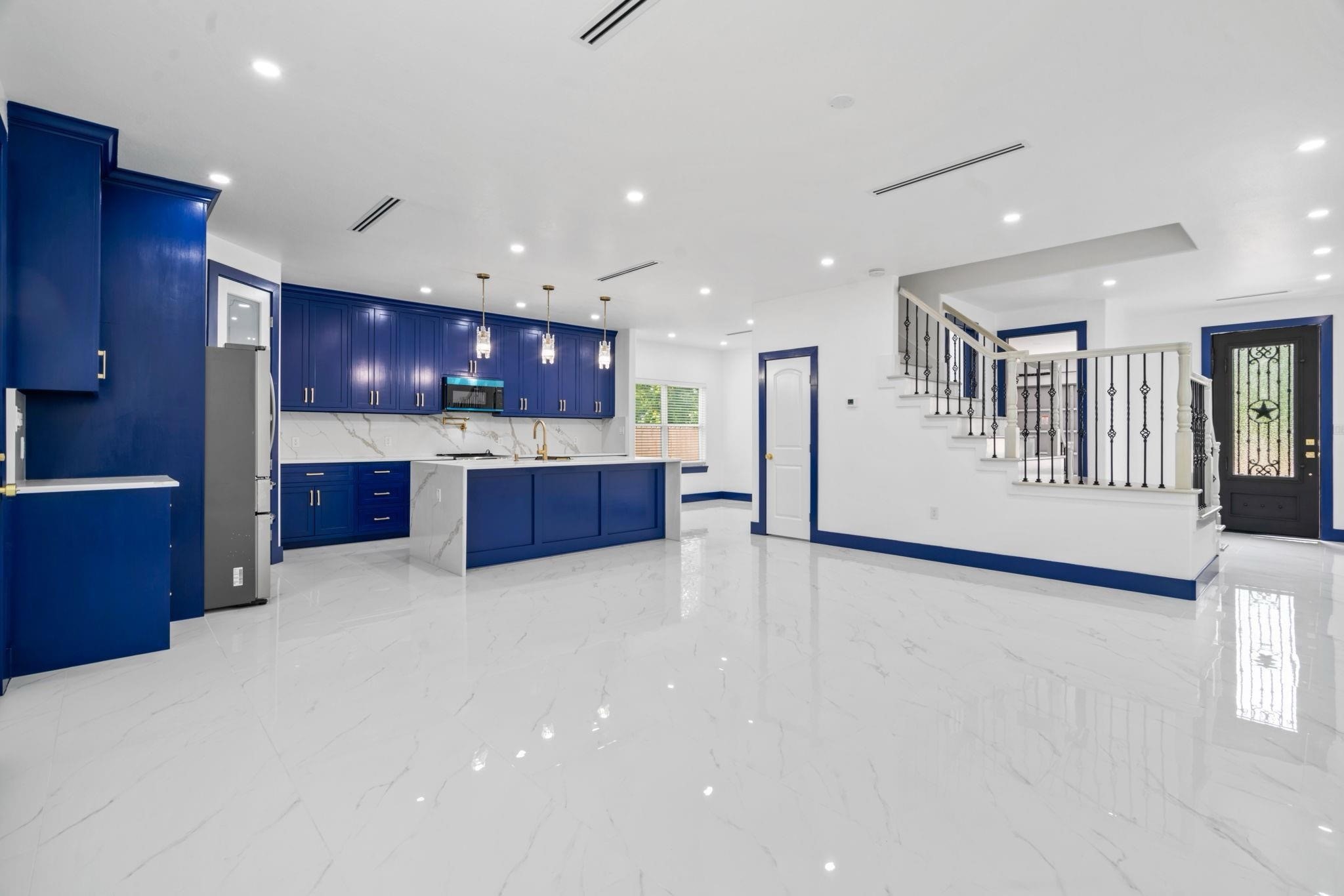 7831 Sandy Street Houston, TX 77028 - Photo 2 of 32 The spacious open-concept layout is highlighted by bold blue kitchen cabinetry, sleek quartz countertops, and porcelain flooring. Recessed lighting and chic pendant fixtures enhance the bright, airy ambiance. An elegant staircase with decorative railing leads to the upper level, while the statement front door adds a touch of character and curb appeal.…