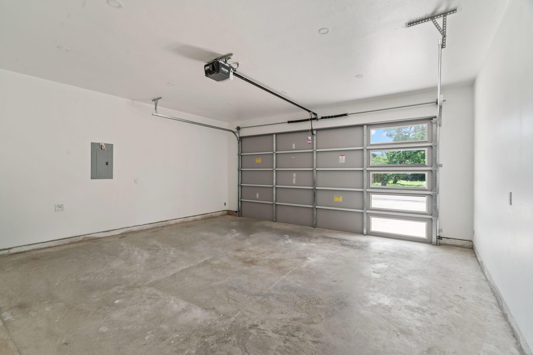7831 Sandy Street Houston, TX 77028 - Photo 25 of 32 A clean, spacious 8-foot-ceiling garage featuring a contemporary overhead garage door with glass panels that allow natural light to flow in. Ideal for parking, storage, or even a home workshop.