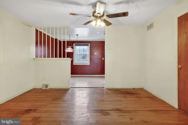 a view of an empty room with window and wooden floor