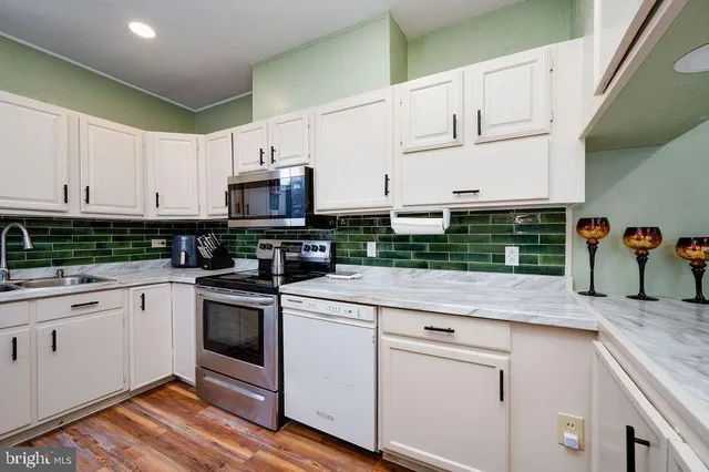 a kitchen with stainless steel appliances granite countertop a stove and white cabinets