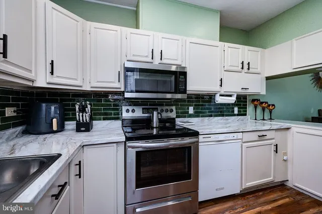a kitchen with granite countertop a stove top oven microwave and cabinets