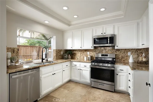 a kitchen with stainless steel appliances kitchen island granite countertop a refrigerator a stove a sink a dining table and chairs with wooden floor