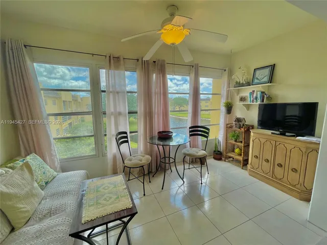 a living room with furniture a flat screen tv and floor to ceiling window