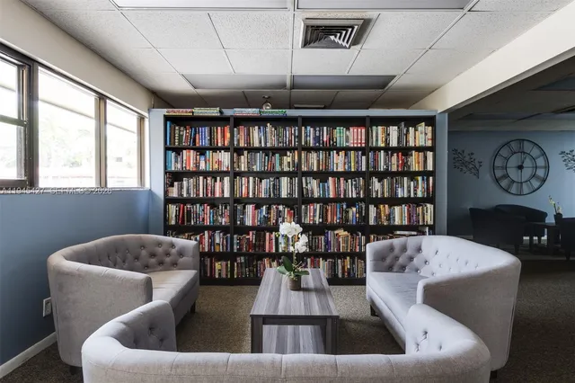 a room with lots of chairs a large clock and a chandelier
