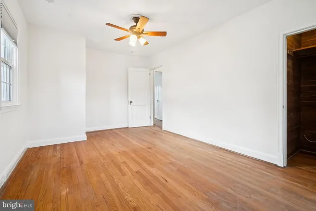 an empty room with wooden floor and ceiling fan