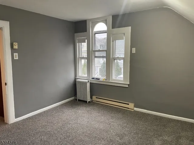 an empty room with windows and chandelier fan