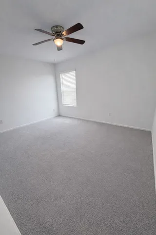 an empty room with a window and a ceiling fan