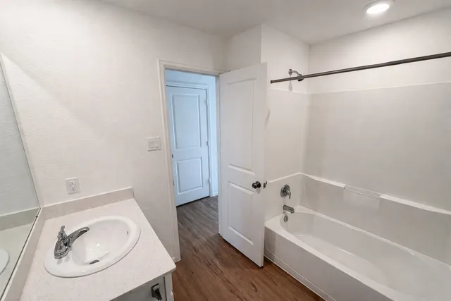 a white bath tub sitting next to a white sink and a mirror