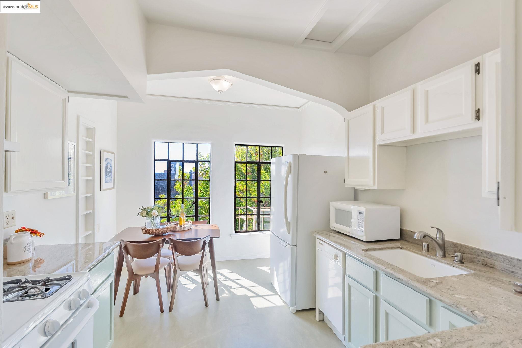 848 Stannage Avenue, Unit 11 Albany, CA 94706 - Photo 11 of 24 Kitchen featuring white appliances, light stone counters, and white cabinetry