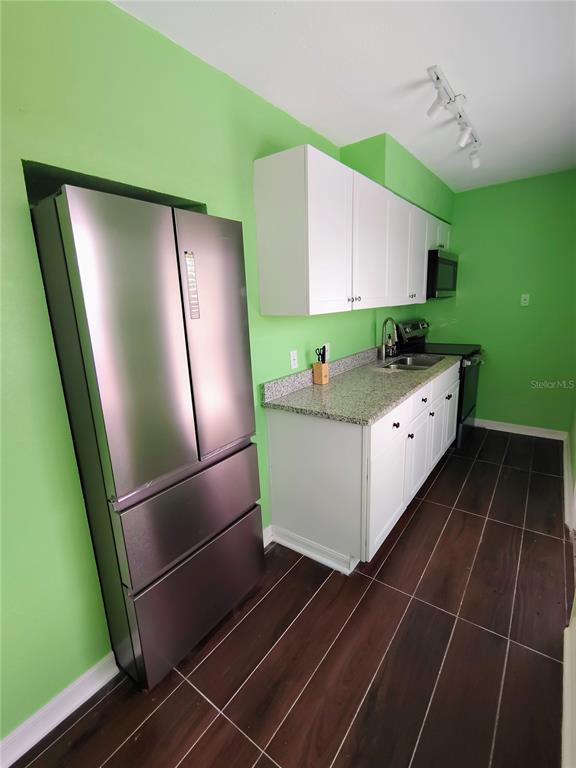 115 145th Avenue, Unit 3 Madeira Beach, FL 33708 - Photo 8 of 12 a kitchen with kitchen island white cabinets a refrigerator and a sink