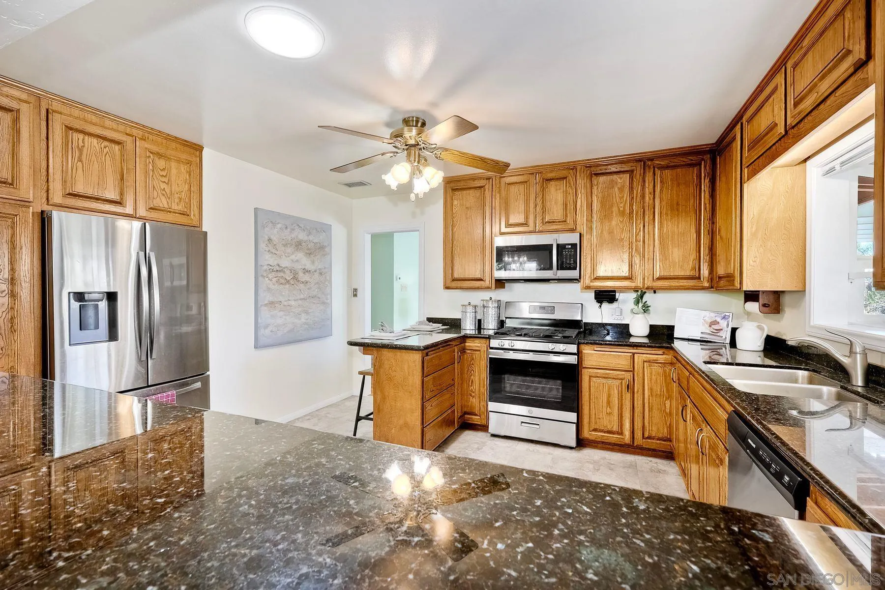 1346 Pepper Villa Drive El Cajon, CA 92021 - Photo 9 of 25 a kitchen with granite countertop a stove top oven a sink dishwasher a refrigerator and a dining table with wooden floor