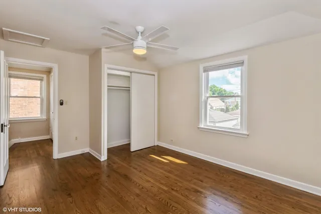 an empty room with wooden floor closet and windows