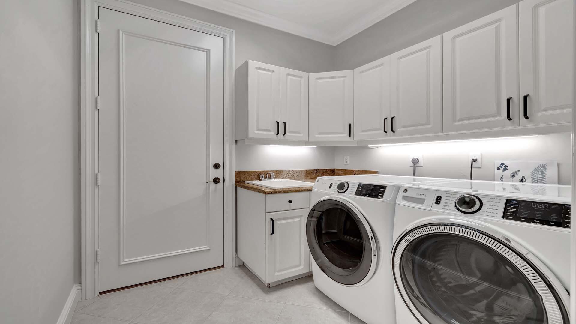 514 Northwest 13th Street Delray Beach, FL 33444 - Photo 30 of 35 a view of washer and dryer with kitchen in the background
