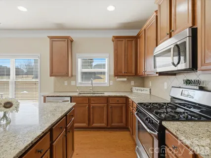 a kitchen with stainless steel appliances granite countertop a sink stove and cabinets