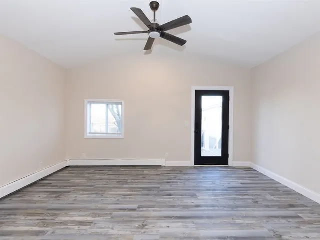 a view of an empty room with window and wooden floor